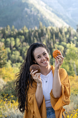 woman holding chocolate chip muffin and small pumpkin